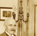 Photo credit: Richard Warren Lipack / Wikimedia Commons. Detail of original Edison chandelier with first form "1880 Wire Terminal Base" sockets and incandescent lamps behind "Edison Pioneer" and 'Edisonian' author Francis Jehl.